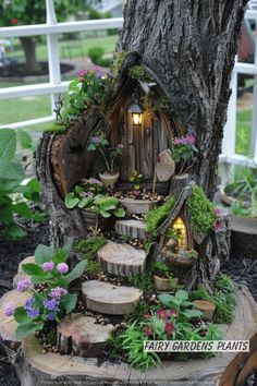 a tree stump with a fairy garden house on it's side and flowers growing out of the hole