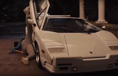 a white sports car parked in front of a house at night with the door open