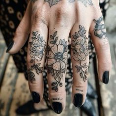 a woman's hand with tattoos and flowers on it