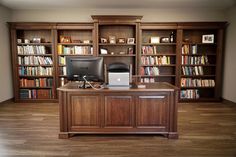 a desk with a computer on top of it in front of bookshelves filled with books