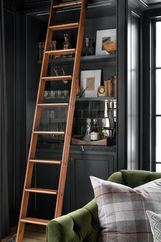 a ladder leaning up against a bookcase in a room with black walls and furniture