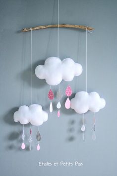 a mobile made out of clouds and raindrops hangs from a twig on the wall