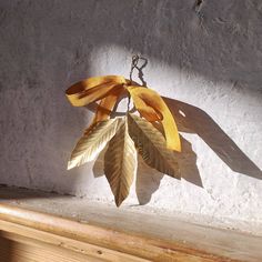 a metal leaf hanging from a chain on a wall