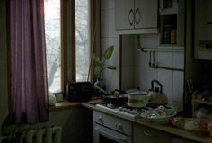 a kitchen with a stove top oven sitting next to a window filled with pots and pans