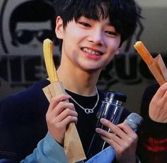 a young man holding up two bananas and a drink in front of his face while smiling at the camera