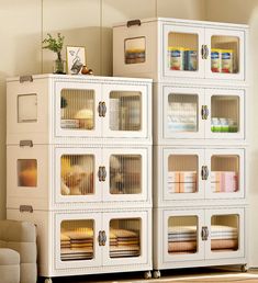 two white storage cabinets with glass doors and drawers on each side in a living room