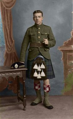 a man in a kilt standing next to a table