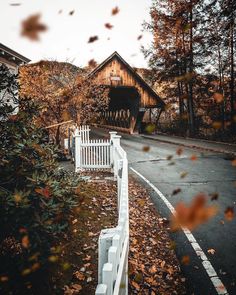 a white bench sitting on the side of a road in front of a wooden building