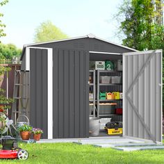 an outdoor storage shed with its doors open and tools in the yard next to it