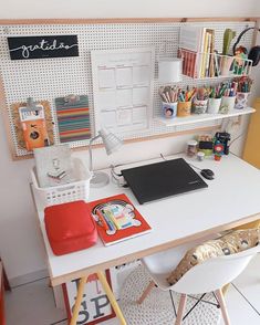 a white desk topped with a laptop computer next to a shelf filled with office supplies