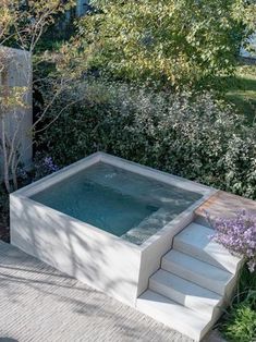 an outdoor hot tub in the middle of a garden with steps leading up to it