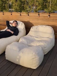 a man laying on top of a white bean bag chair next to a wooden wall