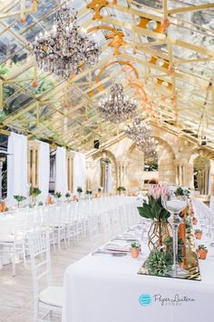 an indoor wedding venue with white tables and chandeliers