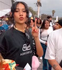 a woman making the peace sign with her fingers while standing in front of a group of people