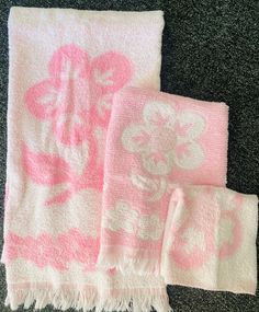 two towels are laying on the floor with pink and white flowers printed on them, next to each other