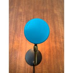 a blue glass ball is sitting on a metal stand with a wooden surface in the background