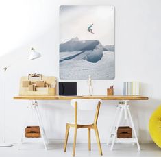 a desk with two chairs and a painting on the wall above it that has a yellow chair in front of it