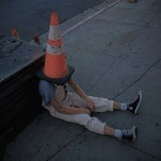 a person laying on the ground next to a traffic cone