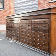 a large wooden dresser sitting on the side of a road next to a brick building