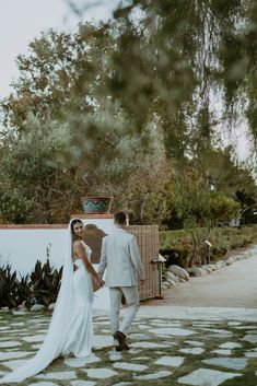 a bride and groom walking through the yard