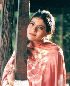 a woman wearing a pink shawl holding a wooden pole