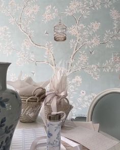 a table with vases, plates and other items on it in front of a wallpapered background