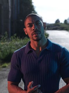 a man standing in front of a road with his hands crossed and looking at the camera