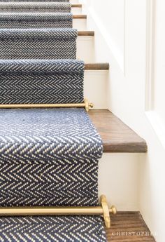 blue and white carpeted stairs with gold handrails in a home hallway or entryway