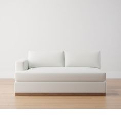 a white couch sitting on top of a hard wood floor next to a white wall