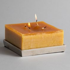 a candle that is sitting on top of a square piece of wax and some sort of substance