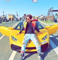 a man sitting on top of a yellow sports car