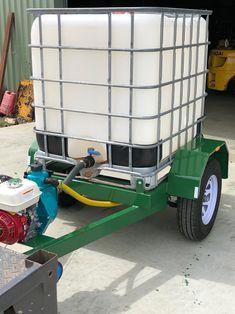 a green trailer with a white tank on it's back and two yellow hoses attached to the side