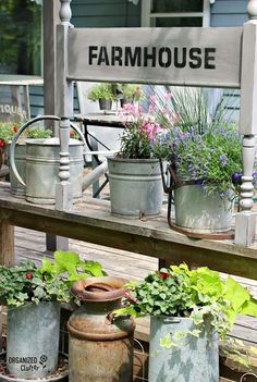 an old fashioned farm house is filled with potted plants and watering canisters