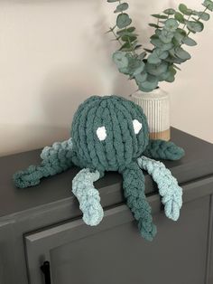 an octopus stuffed animal sitting on top of a dresser next to a potted plant