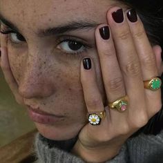 a close up of a person holding their hand to her face with rings on it