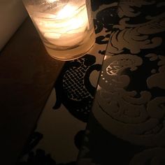 a lit candle sitting on top of a table next to a wallpapered floor