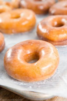 glazed doughnuts sitting on top of a baking sheet