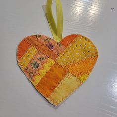 a heart shaped ornament hanging from a yellow ribbon on top of a table