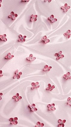 pink flowers are floating in the water on top of a bed sheet that has been made with satin material