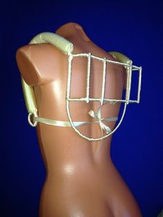 a mannequin wearing a metal caged headpiece on it's back