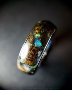 an opalite ring sitting on top of a black surface with light coming through it