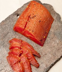 two pieces of raw salmon sitting on top of a stone slab next to each other