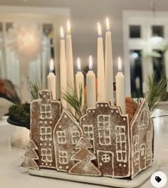 a gingerbread house candle holder with lit candles in the center, on a kitchen counter