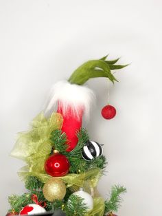 a christmas tree decorated with ornaments and greenery, including an elf's hat