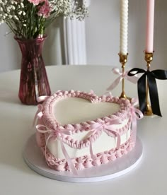 a heart shaped cake sitting on top of a table next to a vase with flowers