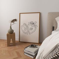 a bedroom with a bed, nightstand and framed artwork on the wall next to it