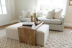 a living room with a couch, coffee table and books on top of the ottoman