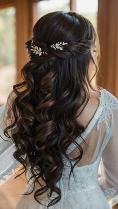 the back of a woman's head with long wavy hair and flowers in her hair