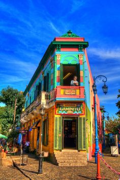 a colorful building with a man sitting in the window