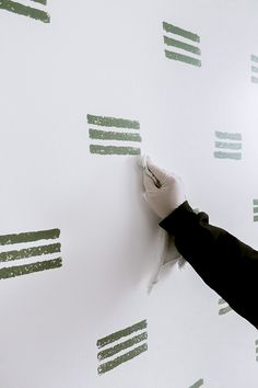 someone is painting the wall with green and white stripes on it's wallshadow